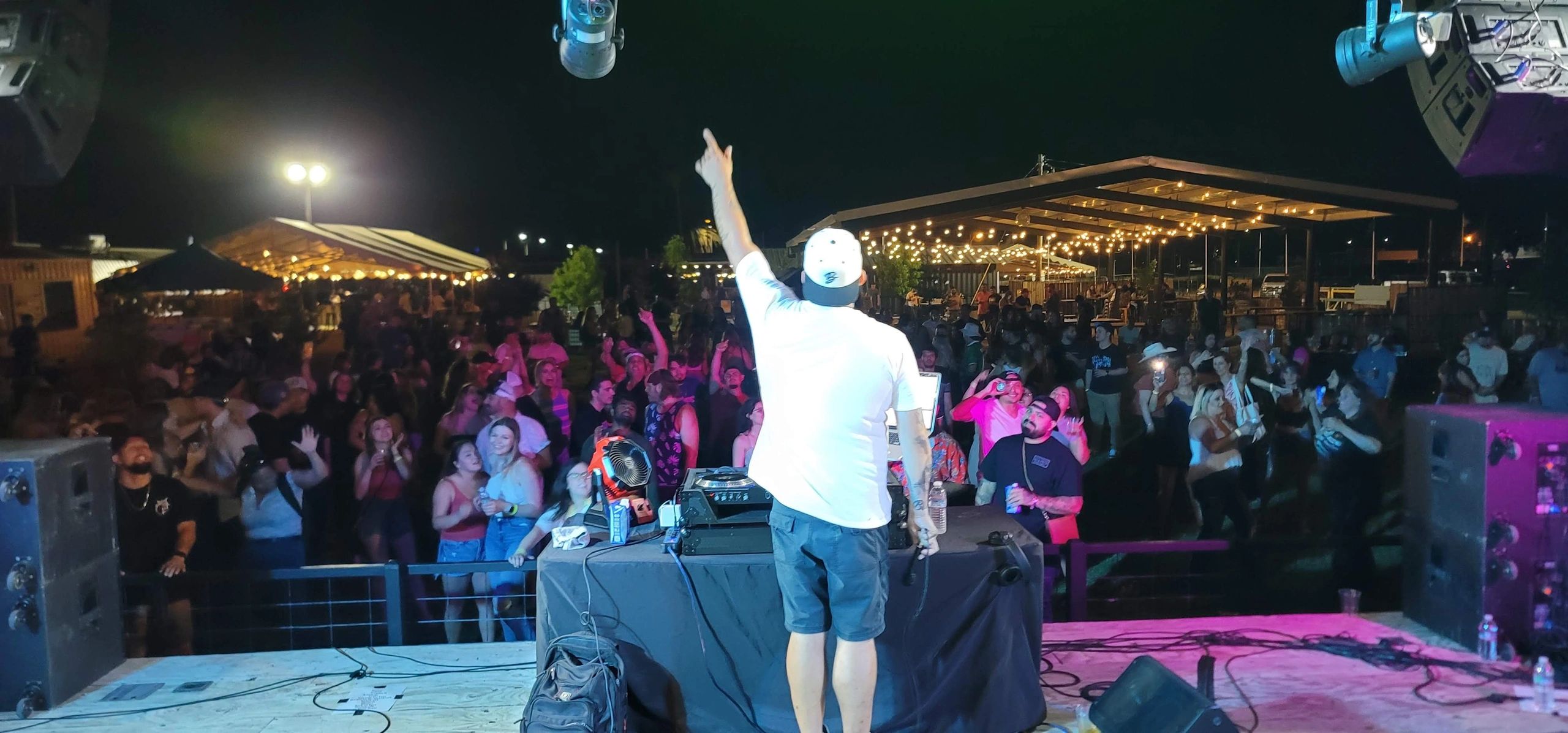 DJ T.A.G. on stage facing a large outdoor crowd